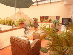 a room with chairs and potted plants and an umbrella at Hostal NIZZA in Cuenca