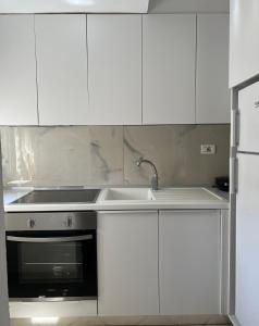 a kitchen with white cabinets and a sink and a stove at Grediv Apartment Orikum in Orikum +2 photos