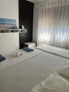 a white bedroom with two beds and a window at Grediv Apartment Orikum in Orikum
