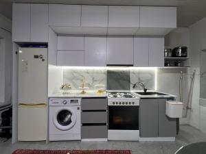 a kitchen with a stove and a washing machine at Archa Ethno Guest House in Bokonbayevo