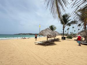 a beach with chairs and umbrellas and the ocean at STEPS TO THE BEACH 2 Stunning condo 4 min walk to Bibijagua Beach and Catamarans in Punta Cana
