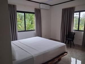 a bedroom with a bed and a chair and windows at Zeph self catering in Baie Lazare Mahé