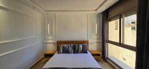 a small bedroom with a bed and a window at Cosy Duplex, Pool & Free Parking Steps to Beach in El Harhoura