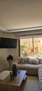 a living room with a couch and a large window at Cosy Duplex, Pool & Free Parking Steps to Beach in El Harhoura