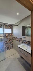 a bathroom with a glass shower and a sink at Cosy Duplex, Pool & Free Parking Steps to Beach in El Harhoura
