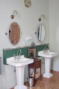two sinks in a bathroom with two mirrors at Demeure Les ragottières in Le Plessis