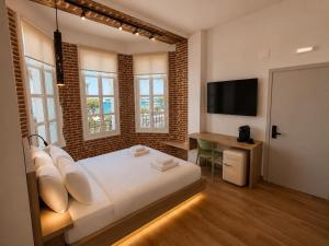 a bedroom with a bed and a desk with a television at Neossiko Chios in Chios