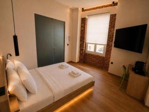 a bedroom with a bed with white pillows and a television at Neossiko Chios in Chios +33 photos
