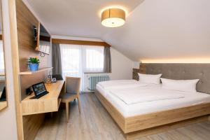 a bedroom with a bed and a desk with a computer at Hotel Anneliese in Bad Hindelang +50 photos