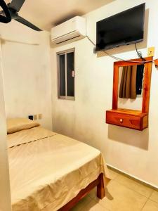 a bedroom with a bed and a flat screen tv at Departamento Refugio Verde in Palenque