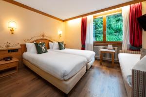 a hotel room with two beds and a window at Hotel Garnì La Montanara in Madonna di Campiglio
