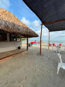 a beach with chairs and a straw umbrella and the ocean at Hotel Boutique Primavera Beach in Necoclí