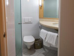 a bathroom with a toilet and a sink and a mirror at Ibis Hermosillo in Hermosillo +63 photos