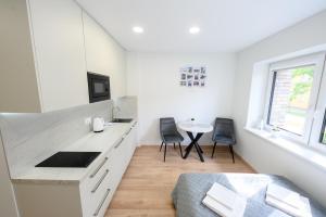 a white kitchen with a sink and a table at NOVA Apartment - 1 in Klaipėda