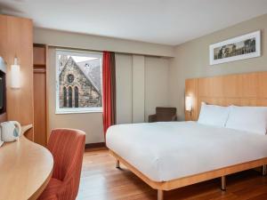a bedroom with a bed and a table and a window at ibis Belfast Queens Quarter in Belfast