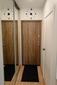 a hallway with two doors with clocks on the walls at NOVA Apartment - 1 in Klaipėda +4 photos