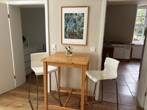 a kitchen with a wooden table and white chairs at Rosenwohnung in Neustrelitz