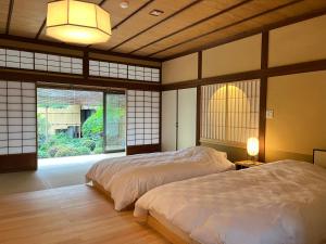 a bedroom with two beds and a large window at Charoku Bekkan in Miyazu