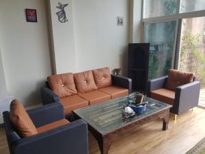a living room with a couch and two chairs and a table at Saadis cottage in Bhurban