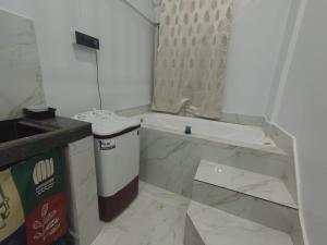 a white bathroom with a tub and a trash can at Lakhimpur Central Homestay - Unmarried couples not allowed in North Lakhimpur