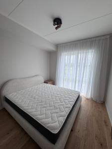 a white bedroom with a bed and a window at Kukerpuu Kinnisvara in Raadi