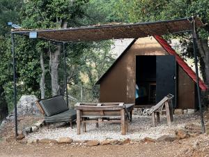 a shelter with a bench and a chair and a table at Kroom cabins in Bâne