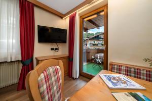 a living room with a table and a television and a window at Hotel Garnì La Montanara in Madonna di Campiglio