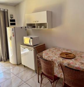 a kitchen with a table and a white refrigerator at Chalé em Maresias - Quintal Privativo - Pet Friendly 4 Hóspedes in Maresias