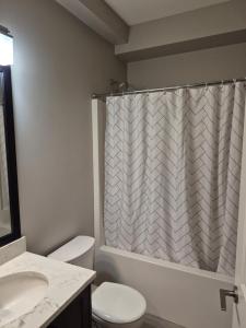 a bathroom with a shower curtain and a toilet at Spacious Private Suite Minutes Away from Ocean,Trails and Stores in Langford
