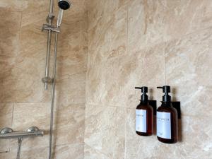 two bottles of soap sitting on a wall in a shower at The Lodge Mews in Shaw Mills +9 photos