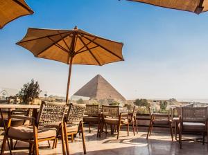 a patio with chairs and an umbrella and a pyramid at Miracle Pyramids View Hotel in Giza