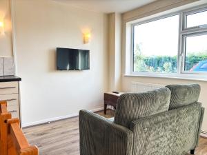 a living room with a chair and a tv on the wall at The Lodge Mews in Shaw Mills