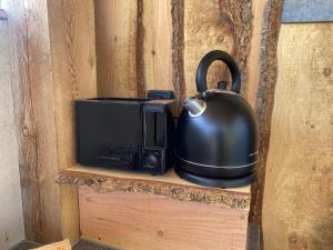 a black tea kettle sitting on top of a microwave at Anno 1782 Unique Romantic Glamping at the Manors Historic Barn in Arnager +25 photos