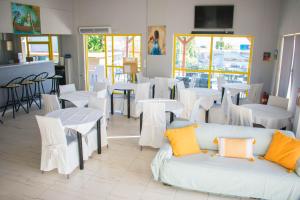 a restaurant with white tables and chairs and a couch at Nereides Hotel in Kolymvari