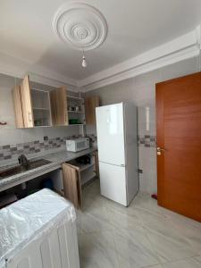 a kitchen with a white refrigerator and wooden cabinets at Mini Villa Azur - Bord de Mer in Driouch