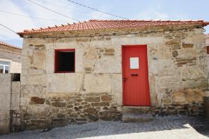 a red door on the side of a stone building at Douro Feels Like Home in Fontelo