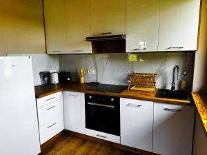 a kitchen with white cabinets and a black stove top oven at Domek nad Oczkiem Wodnym in Giżycko