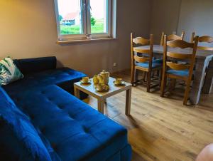 a living room with a blue couch and a table at Domek nad Oczkiem Wodnym in Giżycko
