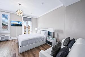 a white bedroom with a bed and a couch at 1BR Retreat with Private Terrace in Palm Beach +32 photos