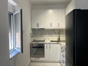 a kitchen with white cabinets and a black refrigerator at FAME Apartment - Permet in Përmet