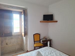 a bedroom with a chair and a tv on the wall at Quinta das Carvalhas in Neiva