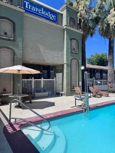 a pool with an umbrella and chairs and a building at Travelodge by Wyndham Redding CA in Redding