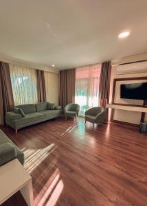 a living room with a couch and chairs and a television at Çamra Otel in Armutlu