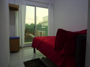 a bedroom with a red bed and a large window at Ndjuly Residencial in Luanda