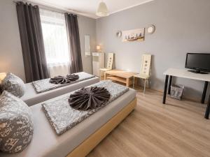 two beds in a room with a desk and a tv at Pension Reiter in Blomberg