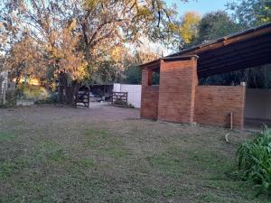 a brick shed in a yard next to a tree at Graciela in Villa Las Rosas