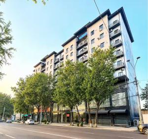 a tall building on a city street with trees at Blueloft 52 I Tashkent City Center in Tashkent