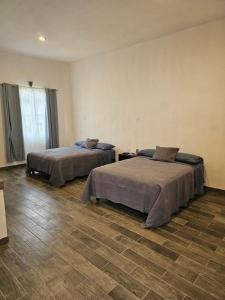 two beds sitting in a room with tile floors at Hotel del Carbón in Villa del Carbón