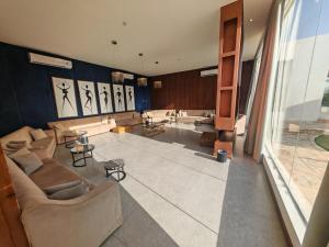 a living room with couches and tables and a large window at Al Salateen Villas Resort in Al ‘Ammārīyah