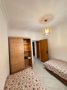 a bedroom with two beds and a cabinet at Appartement Nadin in Martil